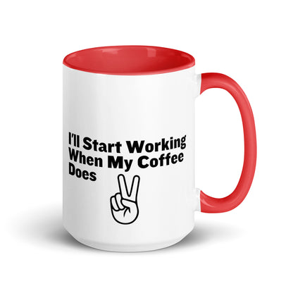 White ceramic mug with a red inside and handle with the words, "I'll start working when my coffee does"