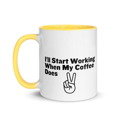 White ceramic mug with a yellow inside and handle with the words, "I'll start working when my coffee does"