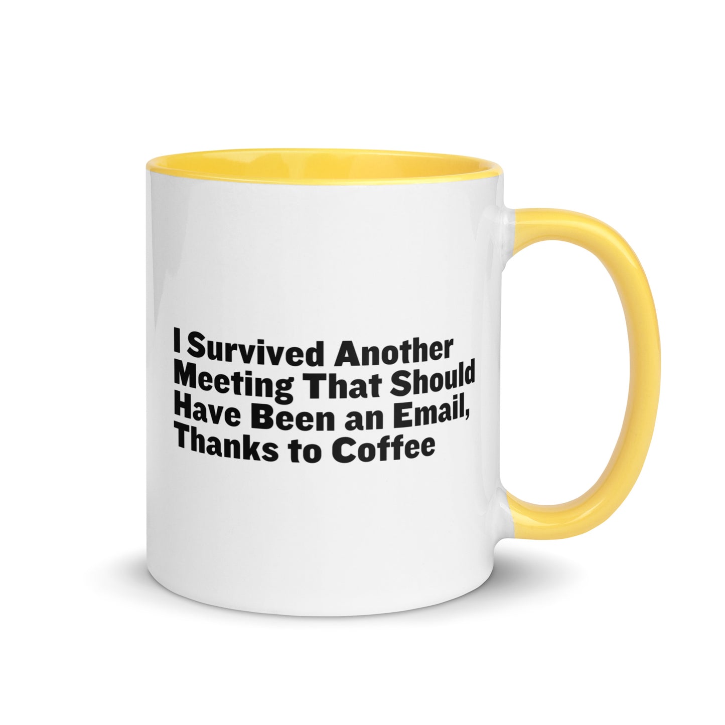 White ceramic mug with yellow inside and on the handle with words that say, "I survived another meeting that should have been an email, thanks to coffee"