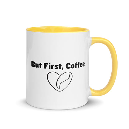 White ceramic mug with yellow on the inside and on the handle with words that say, "But first, coffee"