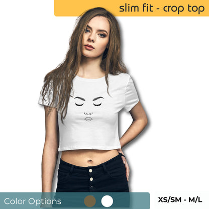 Woman wearing a white slim-fit crop top with a minimalist face line drawing, paired with black high-waisted jeans, highlighting size range XS/SM to M/L.