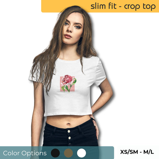 Woman wearing a white slim-fit crop top with a 'Life is Good' rose design, paired with black high-waisted jeans, available in XS/SM to M/L sizes.