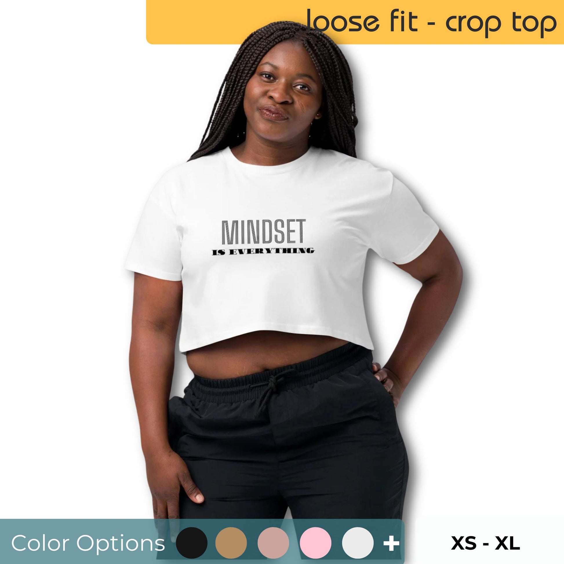 Woman in a white loose-fit crop top with "MINDSET IS EVERYTHING" slogan, paired with black trousers, offering multiple color options, sizes XS to XL.