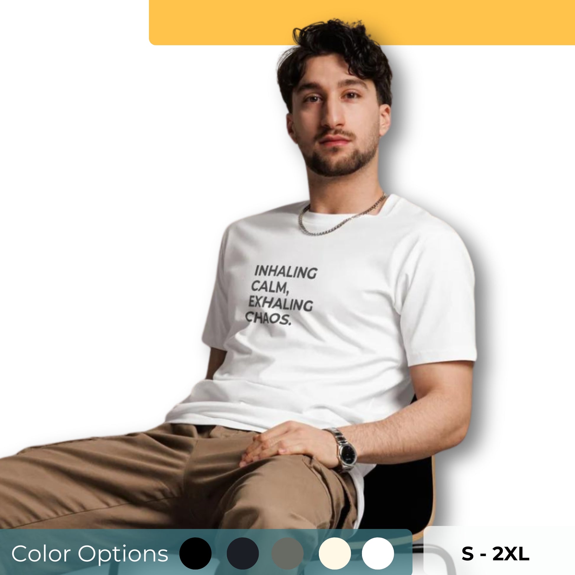 Man sitting wearing a white premium tee with the text "Inhaling Calm, Exhaling Chaos" in various colors and sizes from S to 2XL.