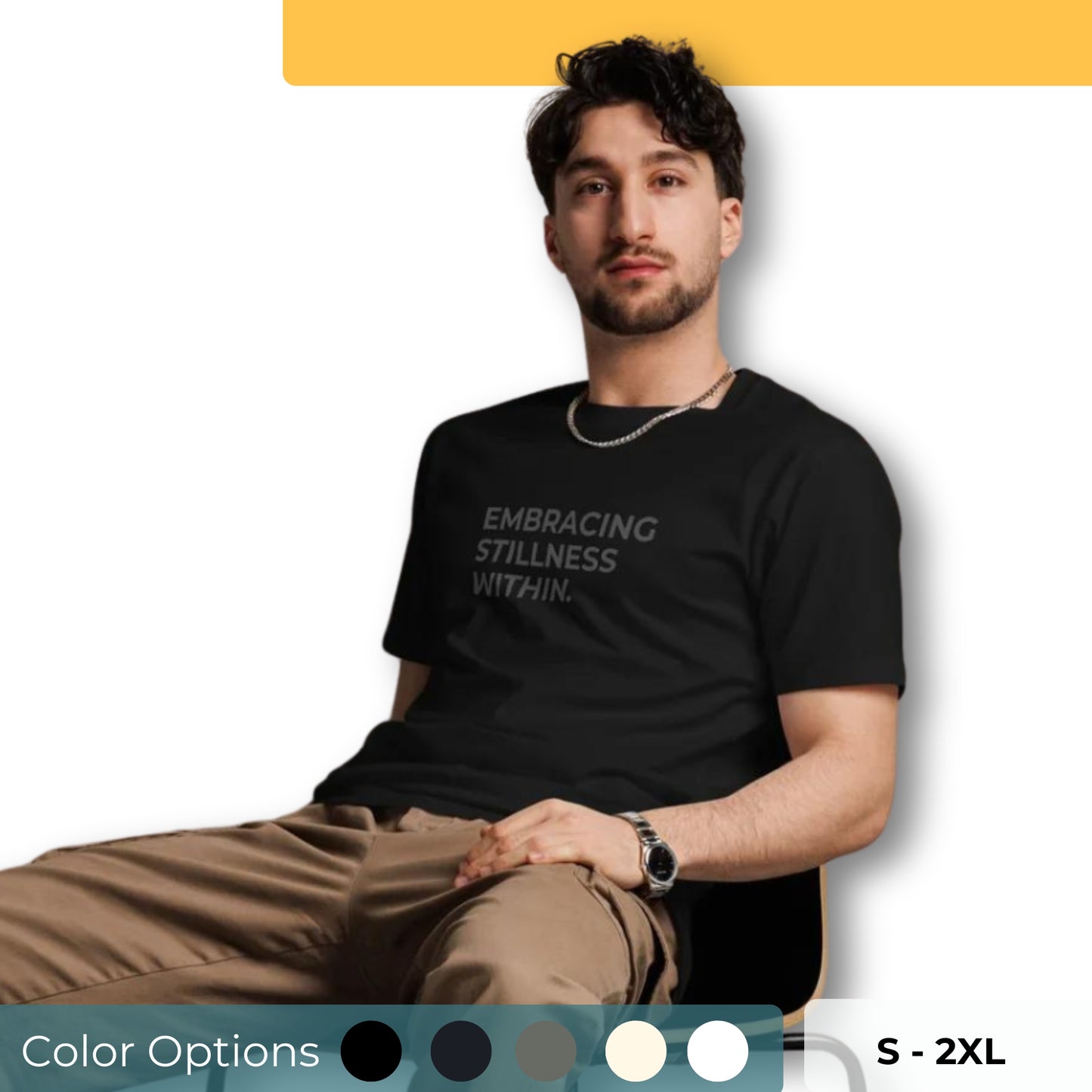 Man sitting wearing a black premium tee with the text "Embracing Stillness Within" in various colors and sizes from S to 2XL.