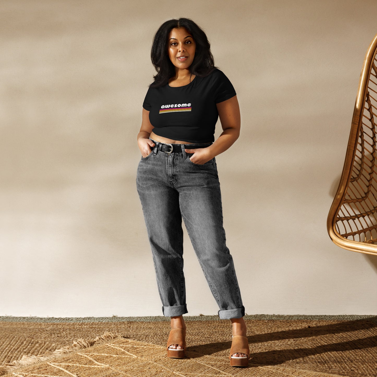 Confident woman wearing a casual black 'Awesome' slogan crop top paired with high-waisted jeans, perfect for a laid-back yet stylish look.