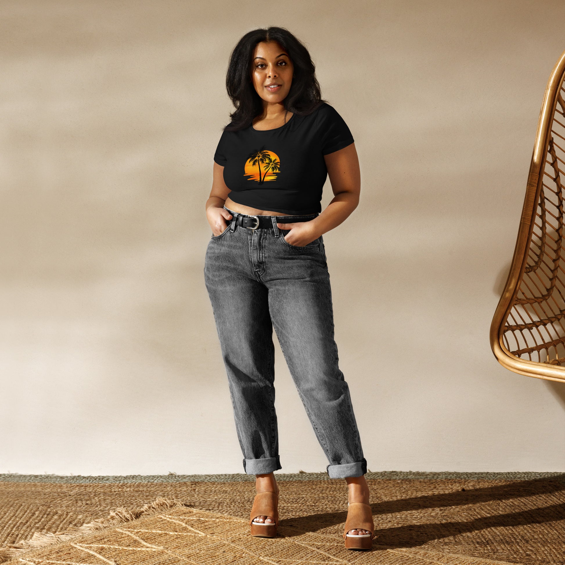 Woman in a black crop top featuring a sunset and palm trees design, embodying a relaxed and inspirational vibe.