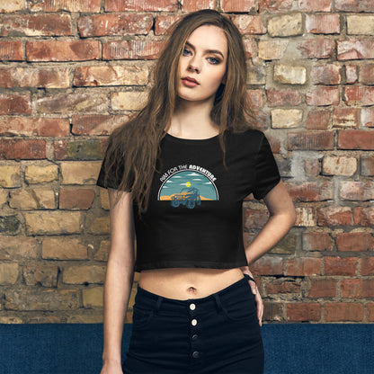 Casual-chic woman in a black crop top with an 'Adventure Awaits' vintage truck graphic, paired with high-waisted black pants.