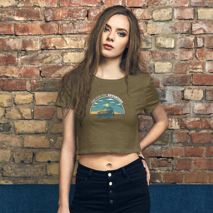 Casual-chic woman in a heathered green crop top with an 'Adventure Awaits' vintage truck graphic, paired with high-waisted black pants.