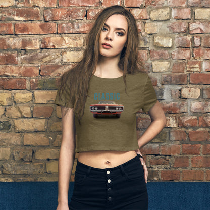 Trendy woman in a heathered grey crop top with a retro classic car graphic, channeling vintage vibes against a brick wall backdrop.