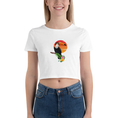 Joyful woman in a white crop top featuring a colorful toucan design against a sunset, perfect for a bold fashion statement.