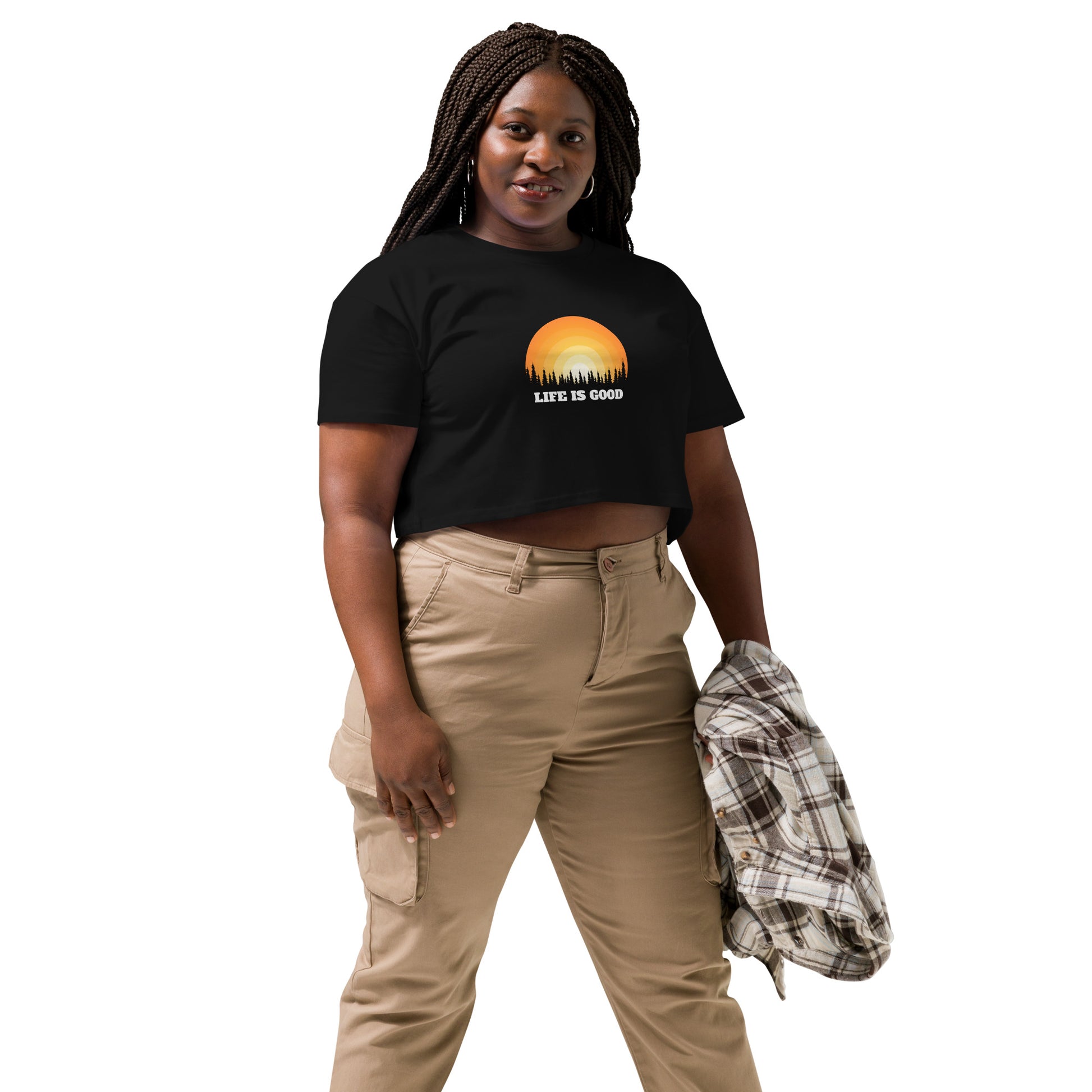 Woman in a black crop top with a "Life is Good" sunset graphic, pairing it with khaki pants and a casual jacket.