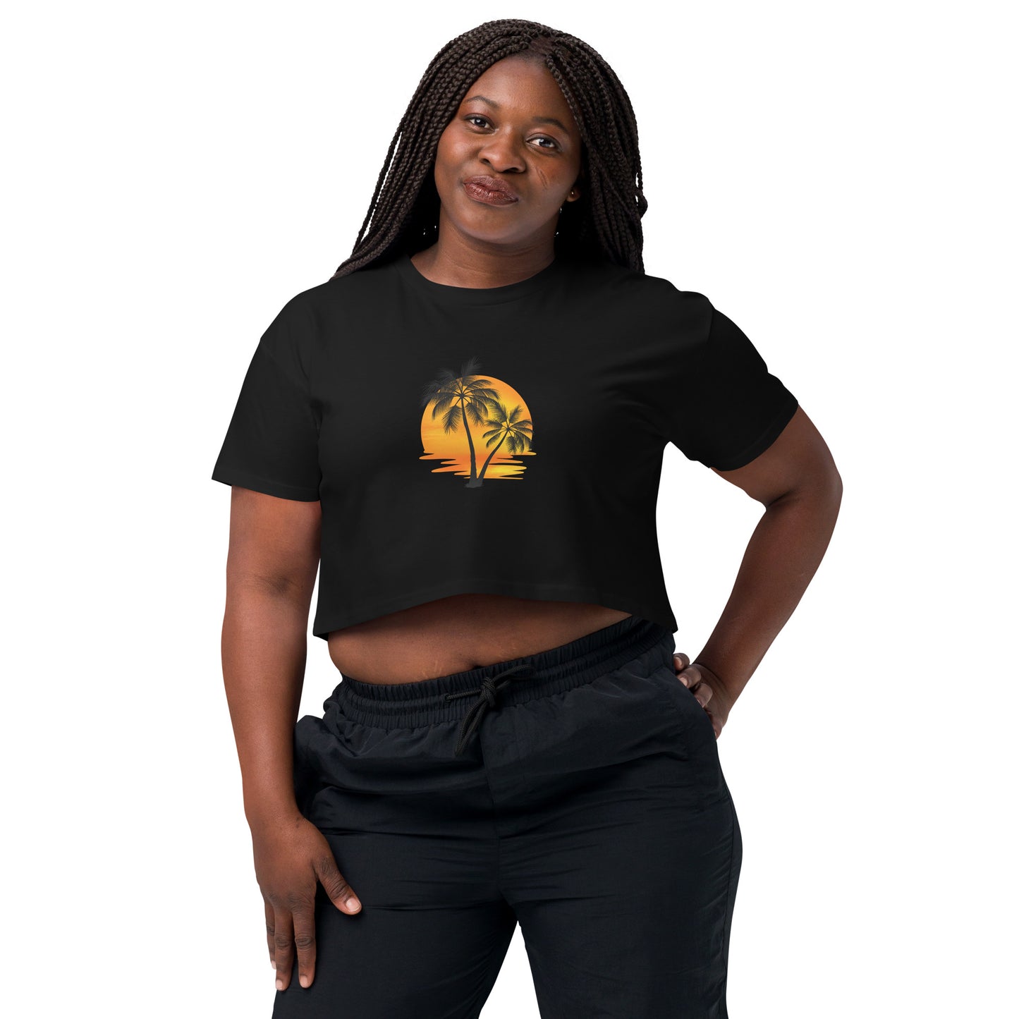 Smiling woman in a black crop top featuring a palm tree silhouette against a sunset, paired with casual black trousers for a laid-back, tropical-inspired look.