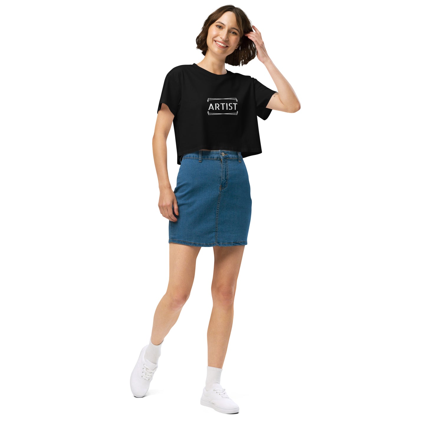 Stylish woman in a back crop top emblazoned with 'ARTIST' in bold font, paired with a denim skirt, projecting a creative and expressive vibe.