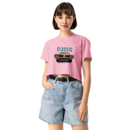 Young woman sporting a bubblegum pink crop top with a classic car graphic design and 'CLASSIC' text, paired with blue denim shorts for a relaxed yet fashionable look.