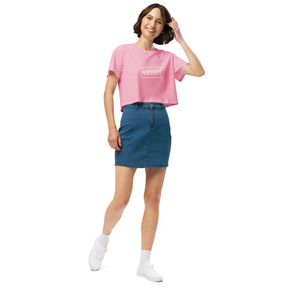 Stylish woman in a bubblegum pink crop top emblazoned with 'ARTIST' in bold font, paired with a denim skirt, projecting a creative and expressive vibe.