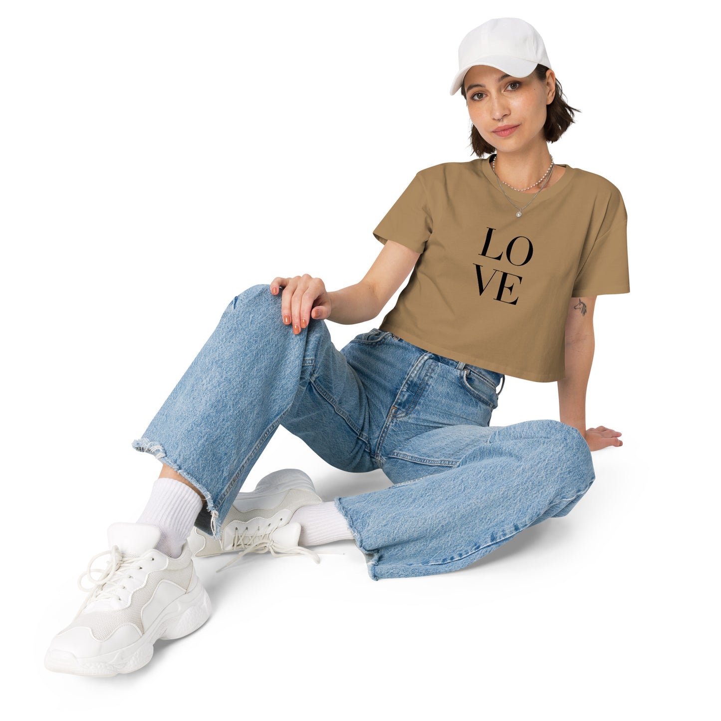 Stylish woman in a camel crop top with bold LOVE print pairing with denim and casual sneakers