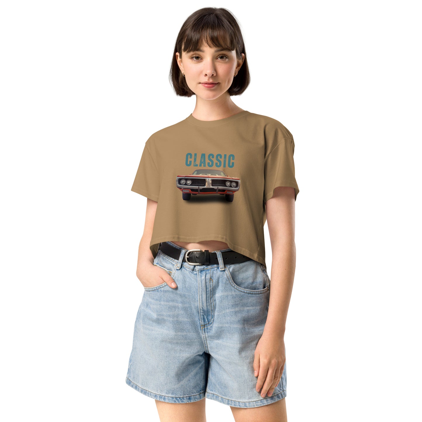 Young woman sporting a camel crop top with a classic car graphic design and 'CLASSIC' text, paired with blue denim shorts for a relaxed yet fashionable look.