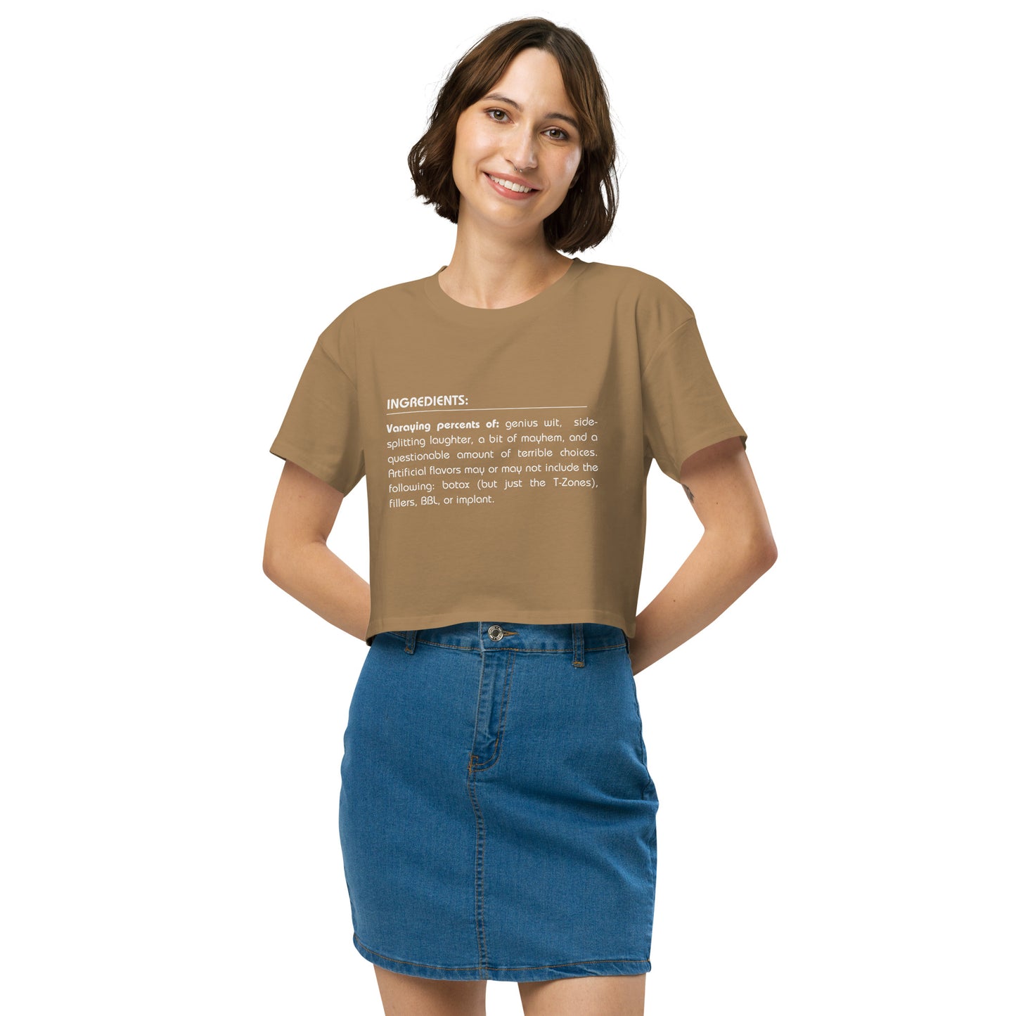 Cheerful woman in a camel crop top featuring a quirky 'Ingredients' list, paired with a denim skirt for a look that combines fun and trendy style.