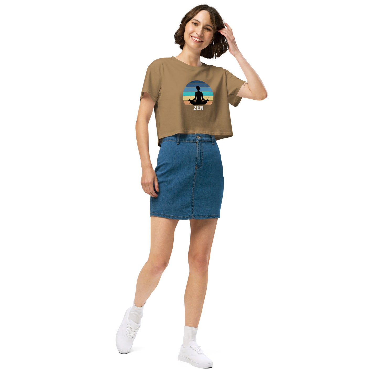 Woman in a camel crop top with a Zen meditation design, paired with a denim skirt and white sneakers