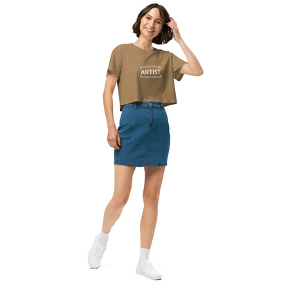 Stylish woman in a camel crop top emblazoned with 'ARTIST' in bold font, paired with a denim skirt, projecting a creative and expressive vibe.