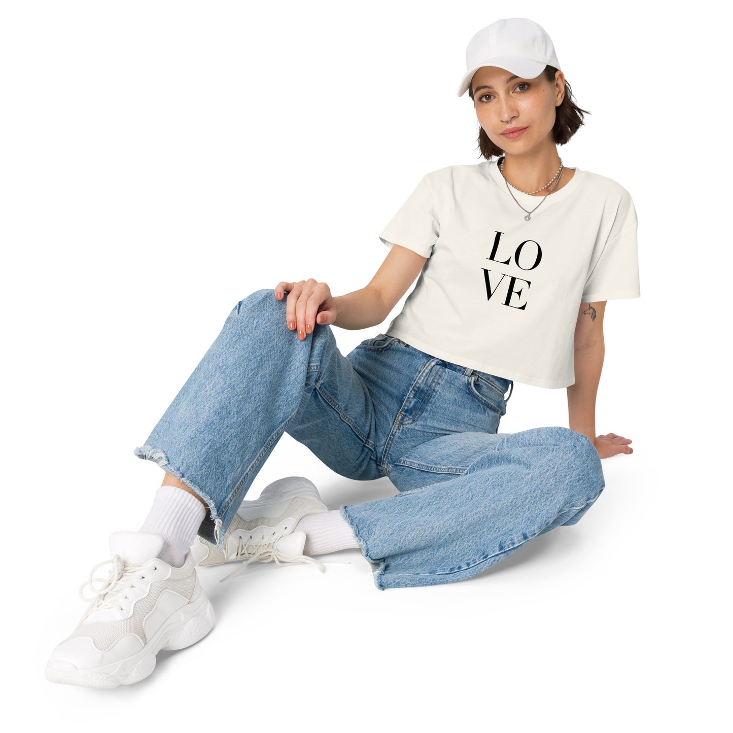 Stylish woman in a ecru crop top with bold LOVE print pairing with denim and casual sneakers