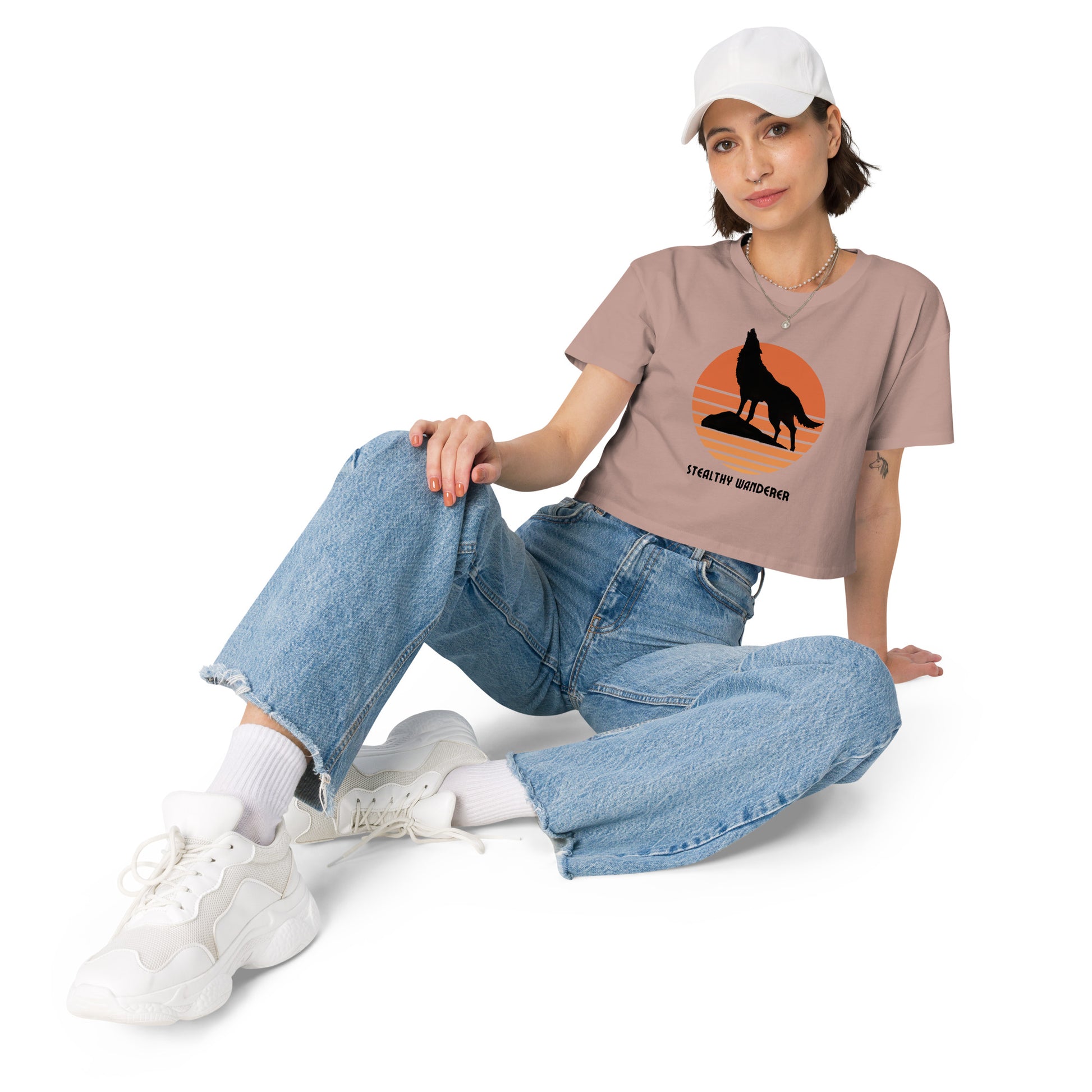 Relaxed woman in a hazy pink crop top with a bold silhouette graphic design, embodying a modern artistic flair and personal expression.