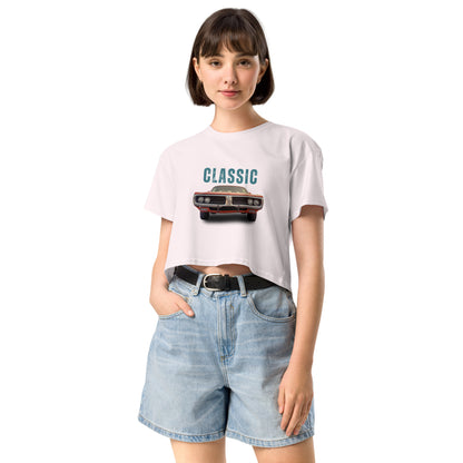 Young woman sporting a pale pink crop top with a classic car graphic design and 'CLASSIC' text, paired with blue denim shorts for a relaxed yet fashionable look.