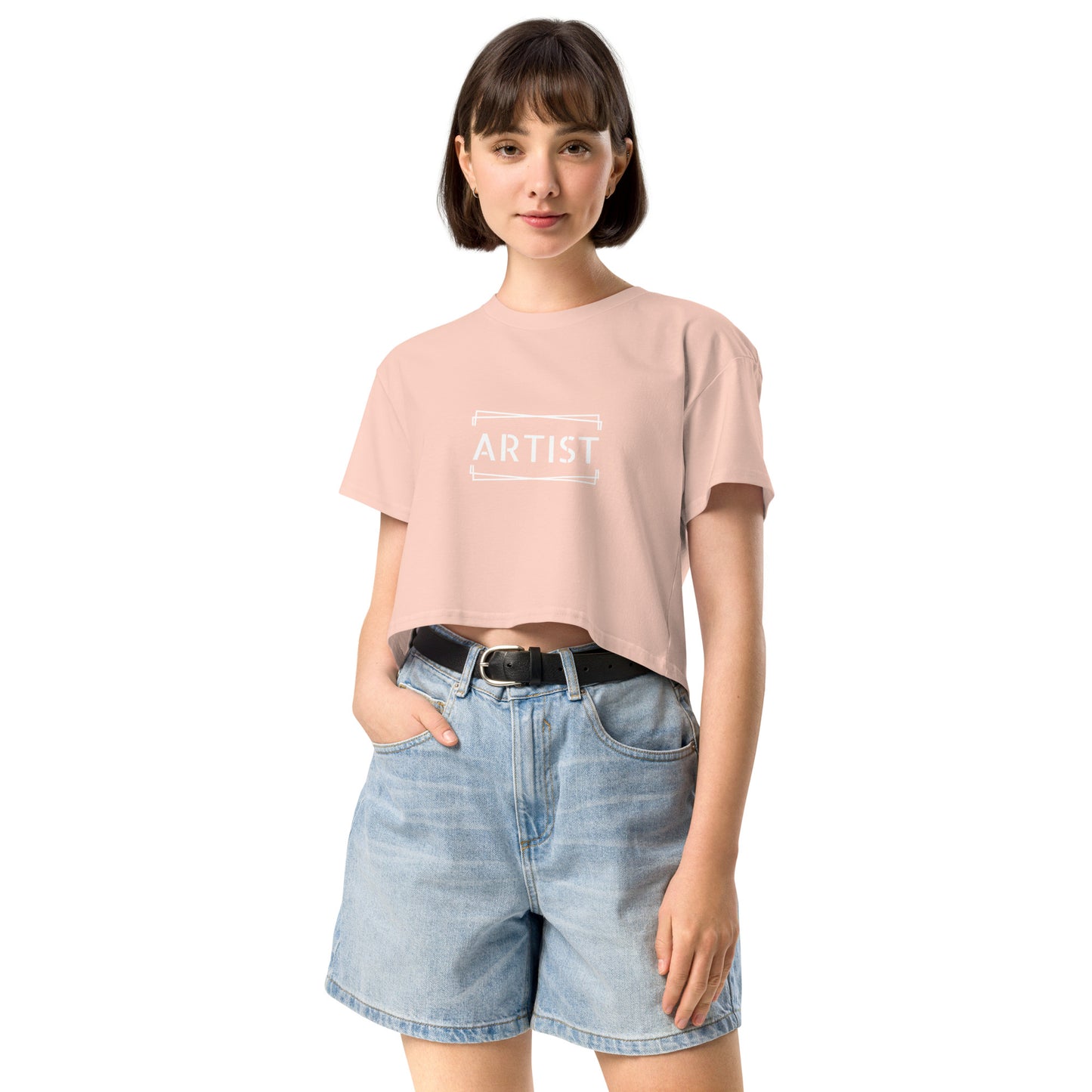 Confident young woman in a pale pink empowering crop top with the word 'ARTIST' printed in white.