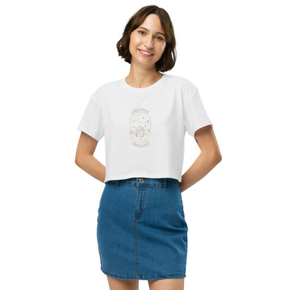 Cheerful woman in a white crop top with 'UNIVERSE UNFOLDER' and celestial design, paired with a denim skirt.