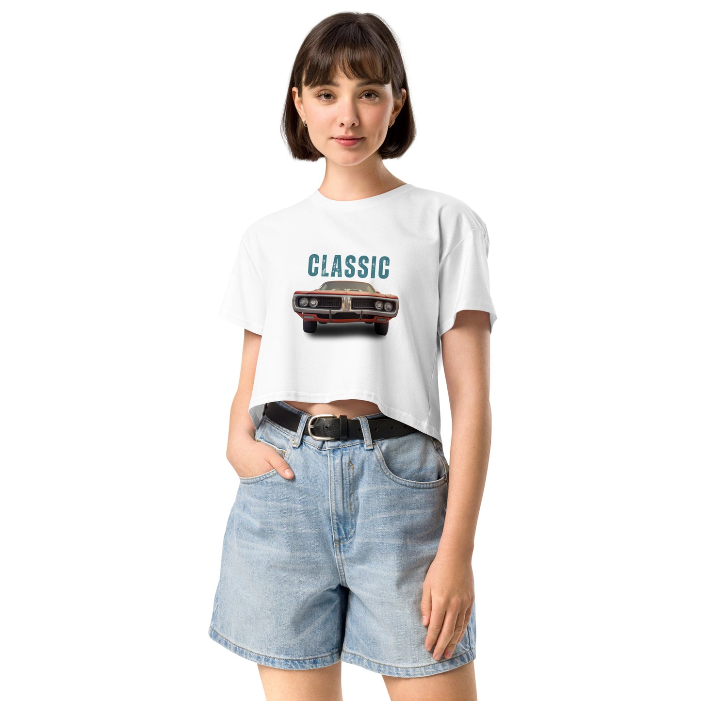 Young woman sporting a white crop top with a classic car graphic design and 'CLASSIC' text, paired with blue denim shorts for a relaxed yet fashionable look.