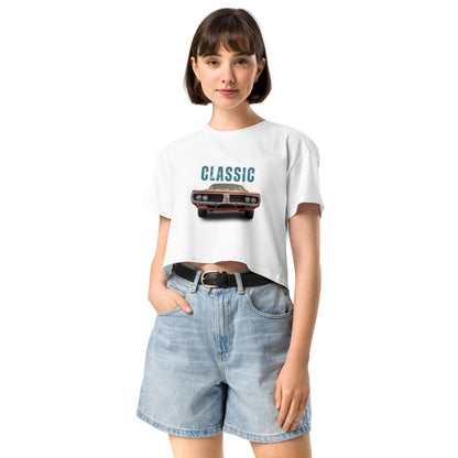 Young woman sporting a white crop top with a classic car graphic design and 'CLASSIC' text, paired with blue denim shorts for a relaxed yet fashionable look.