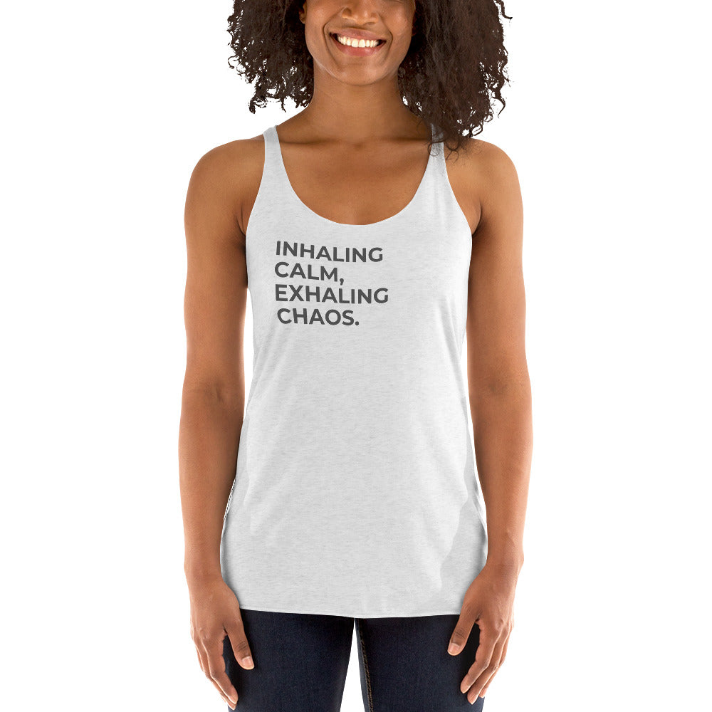 Smiling woman in a heather white racer back tank with "Inhaling Calm, Exhaling Chaos" text.