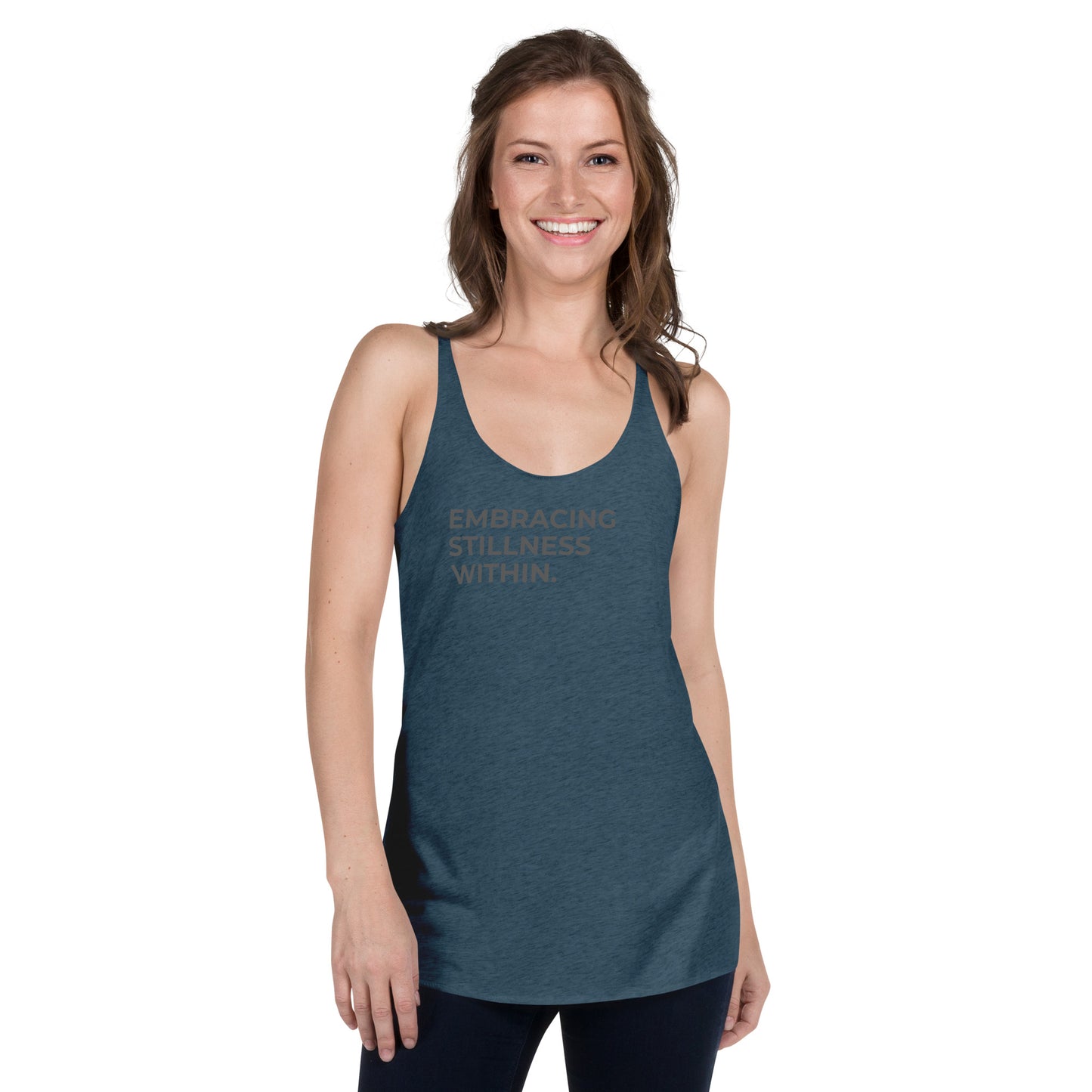 Smiling woman wearing a green racer back tank with "Embracing Stillness Within" text.