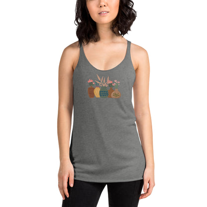 Woman wearing a heather grey racer back tank top with a subtle design of various pots and plants.