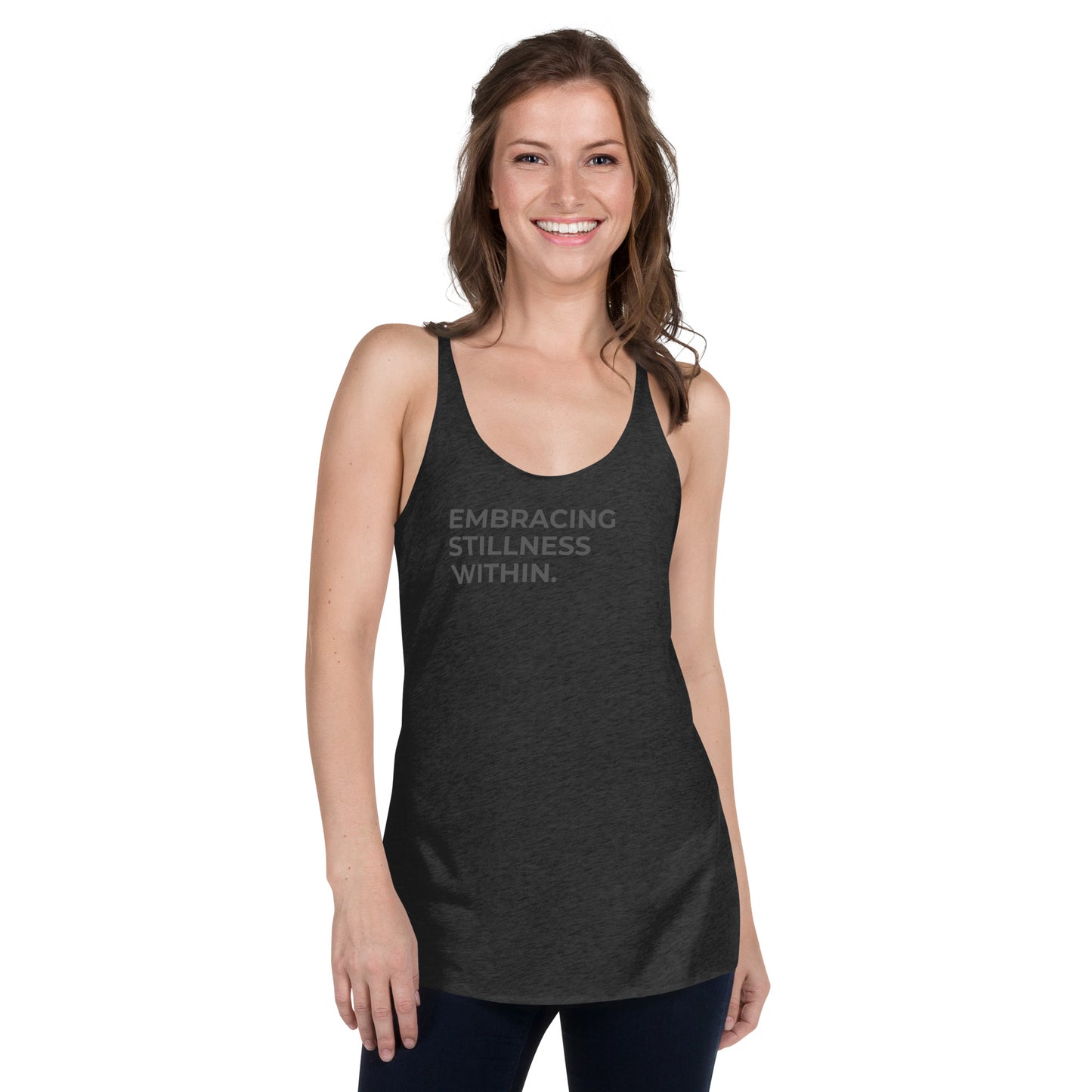 Smiling woman wearing a dark racer back tank with "Embracing Stillness Within" text.