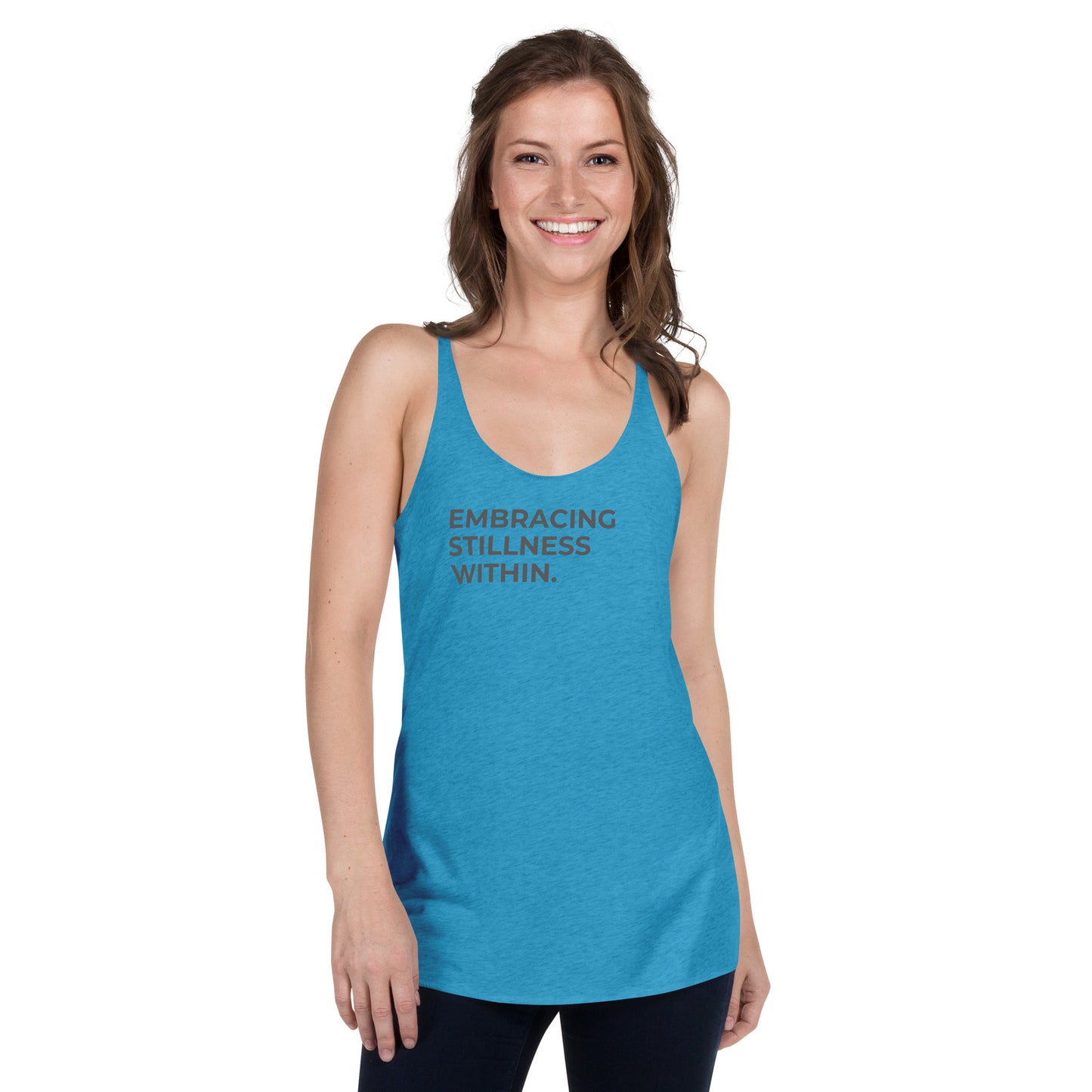 Smiling woman wearing a turquoise racer back tank with "Embracing Stillness Within" text.