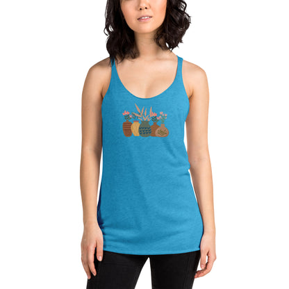 Woman wearing a heather blue racer back tank top with a subtle design of various pots and plants.