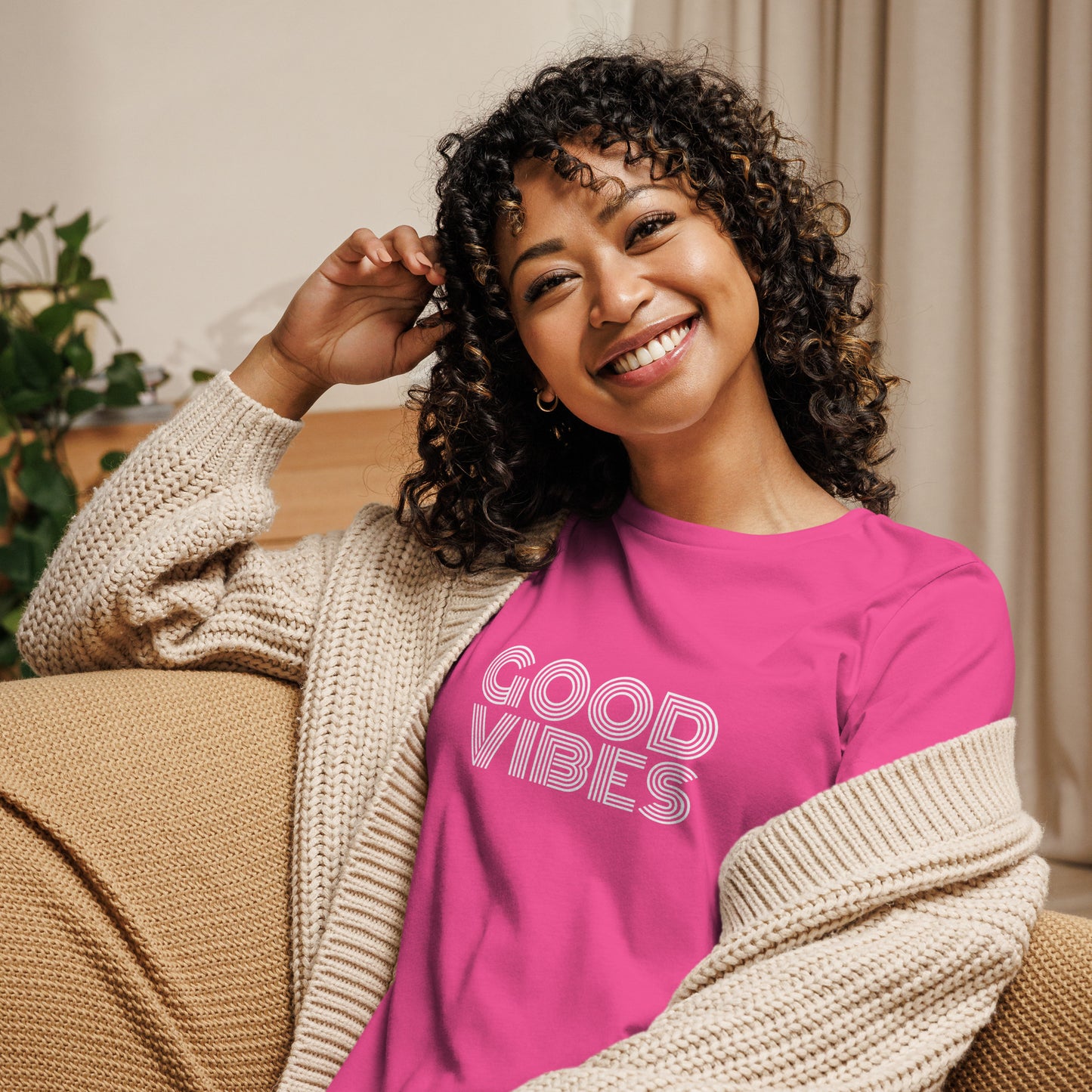 Woman smiling in a berry relaxed t-shirt with "Good Vibes" in white lettering, promoting a positive and cheerful style.