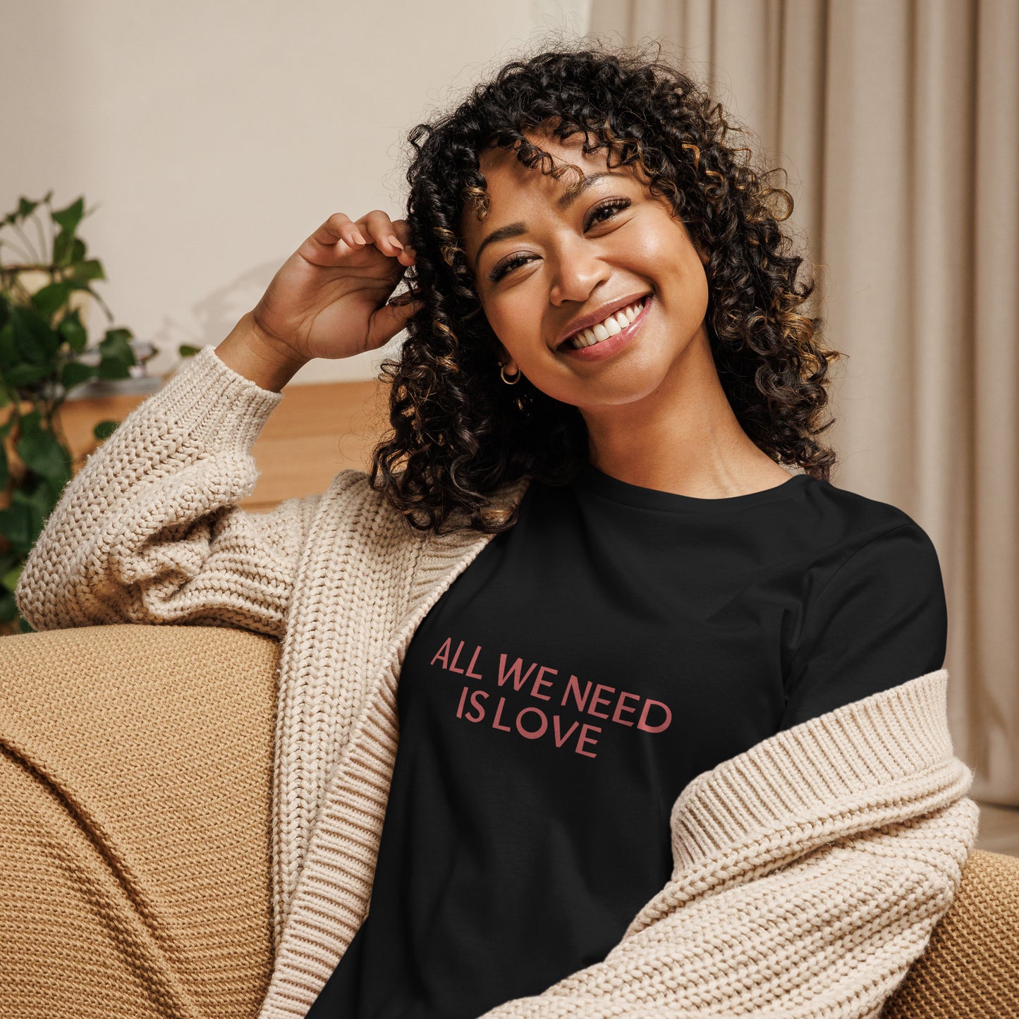 Woman smiling in black relaxed t-shirt with 'All We Need Is Love' phrase