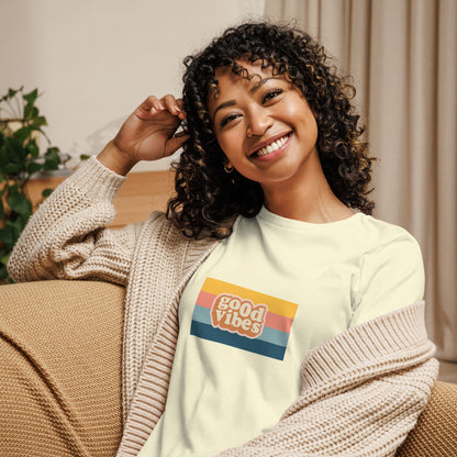 Woman smiling in a white relaxed t-shirt with colorful 'Good Vibes' graphic