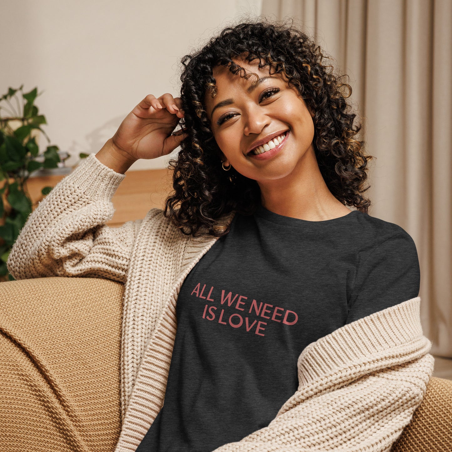 Woman smiling in heather grey relaxed t-shirt with 'All We Need Is Love' phrase