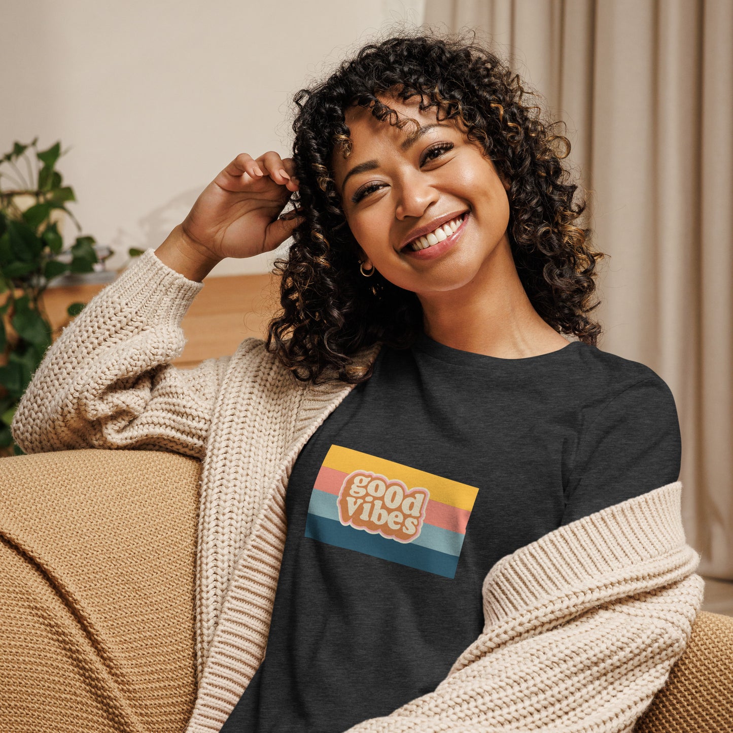 Woman smiling in a heather grey relaxed t-shirt with colorful 'Good Vibes' graphic