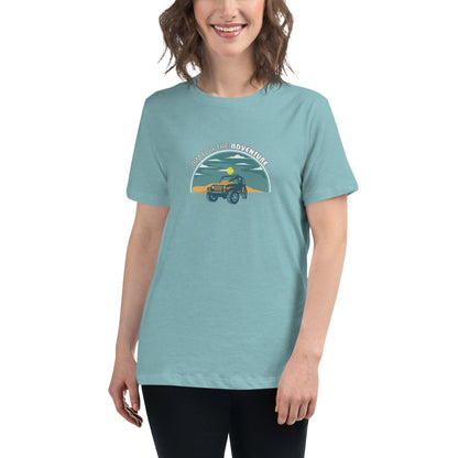 Woman smiling in a heather blue relaxed t-shirt with 'Aim for the Adventure' and a vintage camper graphic