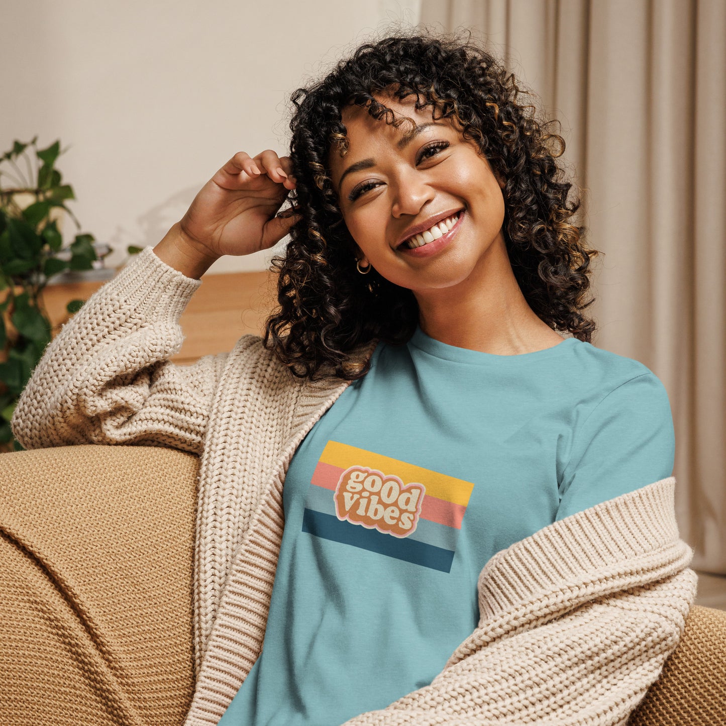 Woman smiling in a heather blue relaxed t-shirt with colorful 'Good Vibes' graphic