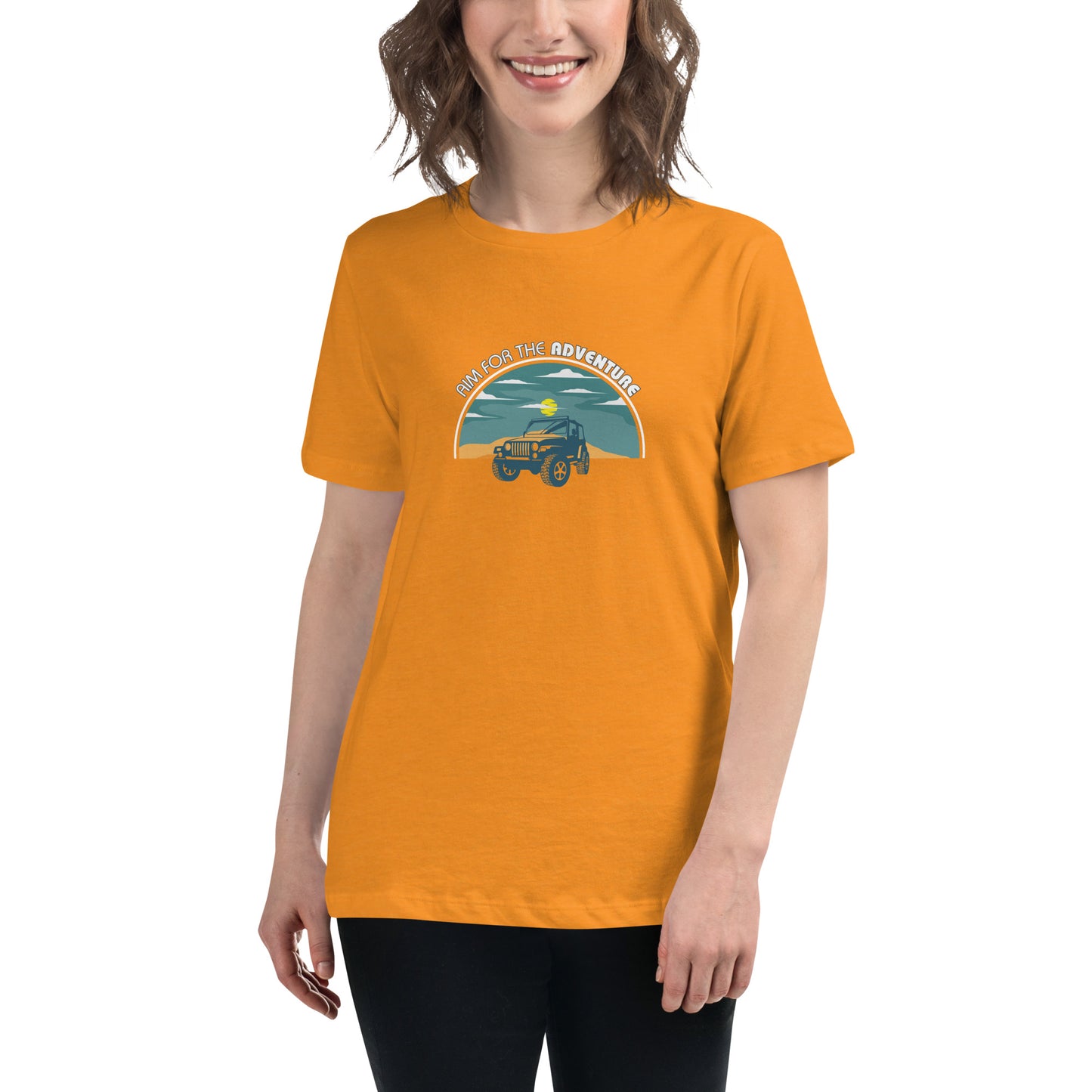 Woman smiling in a heather orange relaxed t-shirt with 'Aim for the Adventure' and a vintage camper graphic