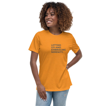 Woman wearing a heather marmalade relaxed tee with "Letting Go and Embracing Serenity" printed, available in various colors and sizes from S-3XL.