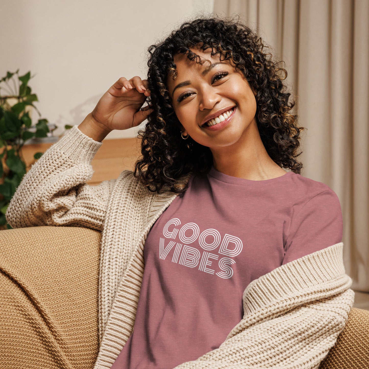 Woman smiling in a heather mauve relaxed t-shirt with "Good Vibes" in white lettering, promoting a positive and cheerful style.