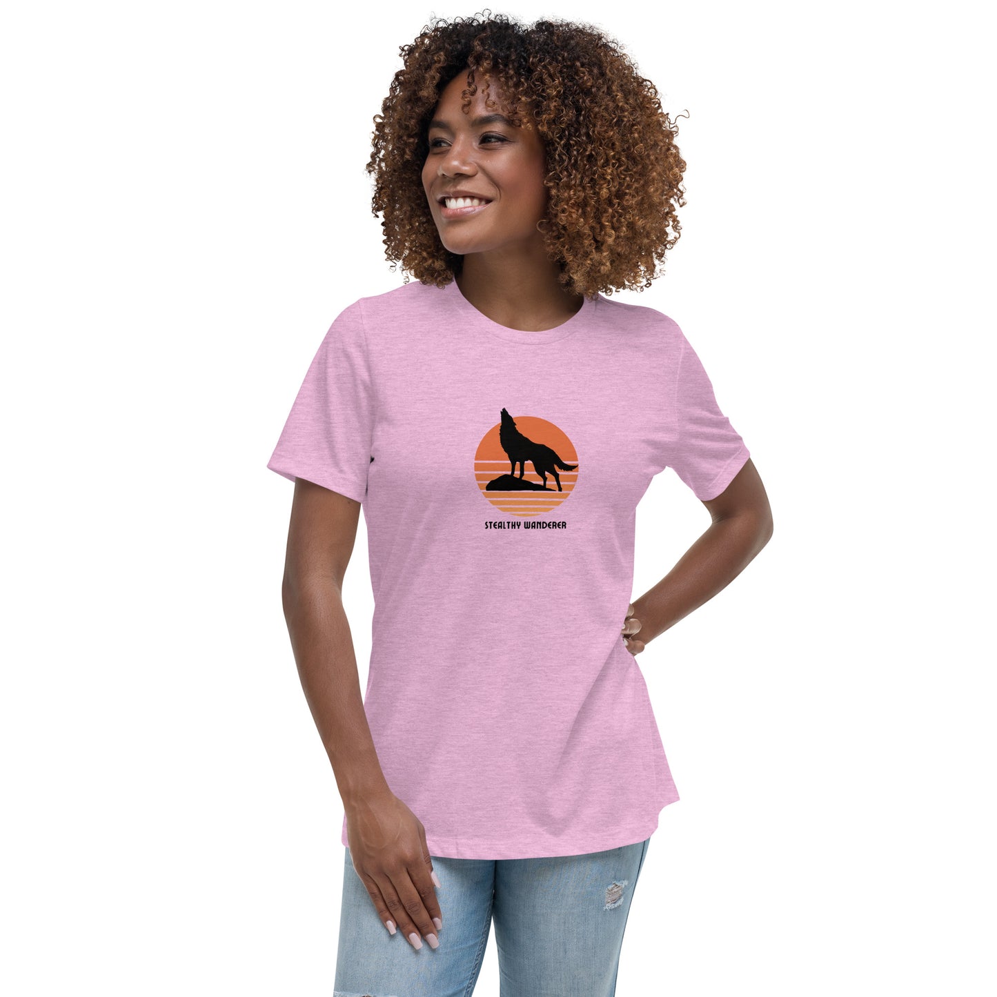 Woman wearing a heather lilac bravery-themed relaxed t-shirt with a wolf graphic and 'Stealthy Wanderer' text in a sunset backdrop