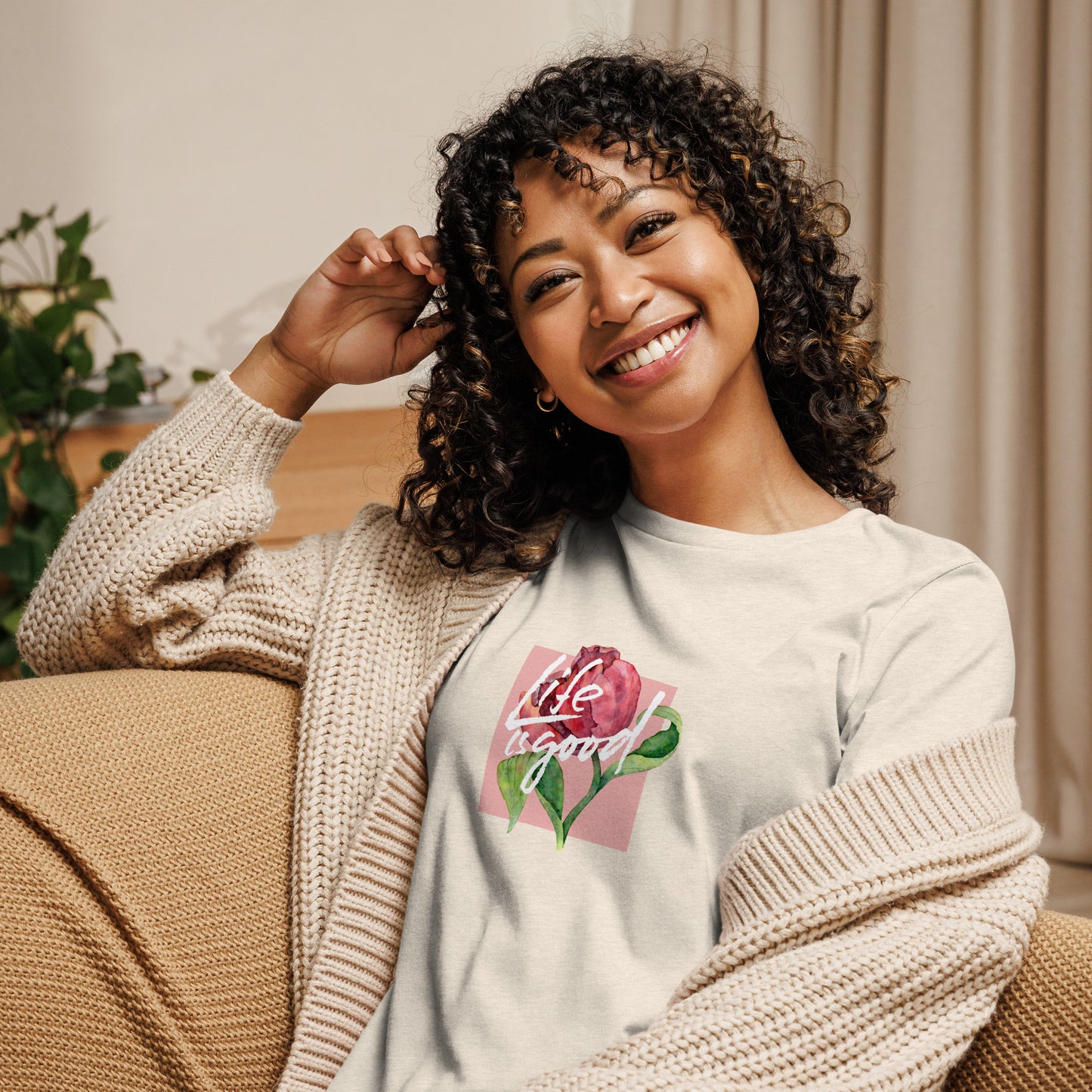 Woman smiling in a heather natural relaxed t-shirt with colorful 'Life in Bloom' floral design